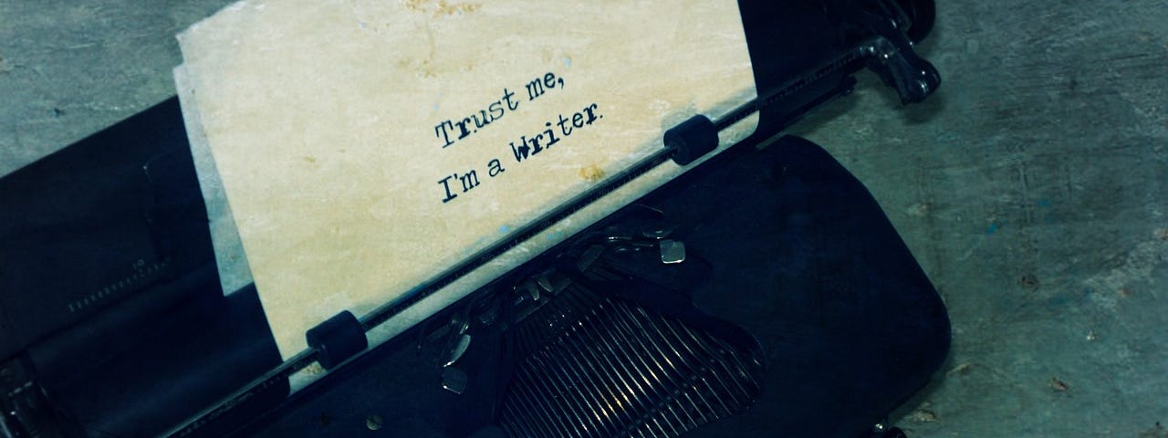Sheet of paper emerging from a typewriter, with the words, “Trust me, I’m a Writer.”