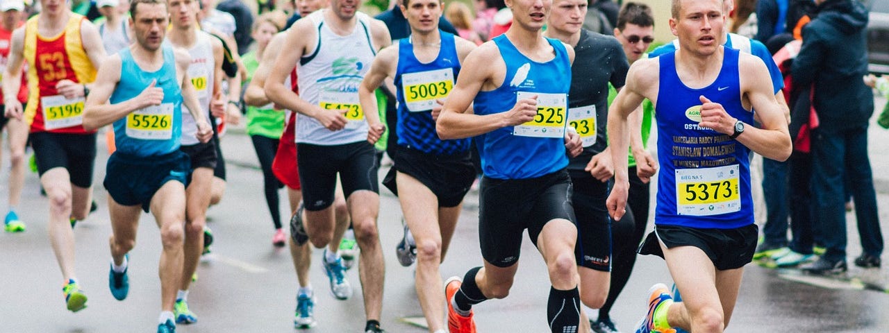 A group of runners at the front of a race running rather fast.