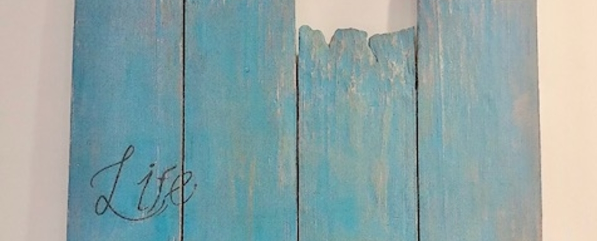 A piece of wood panels with turquoise blue at the top and gray  at the bottom, with the wordings of ‘Life Is Beautiful’ in the center.