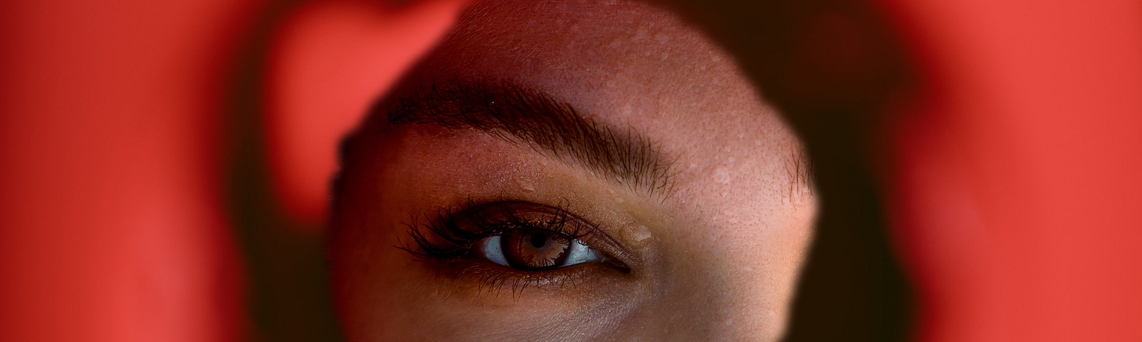 A person’s eye viewed through a hole in the wall