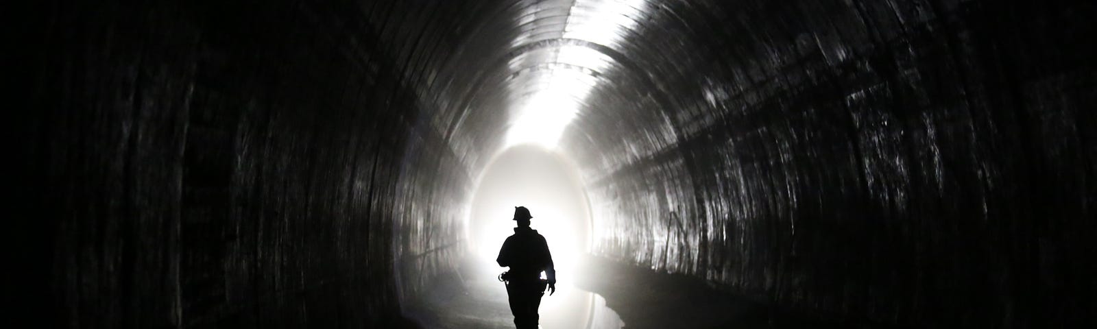 A worker walks in a tunnel towards the background.