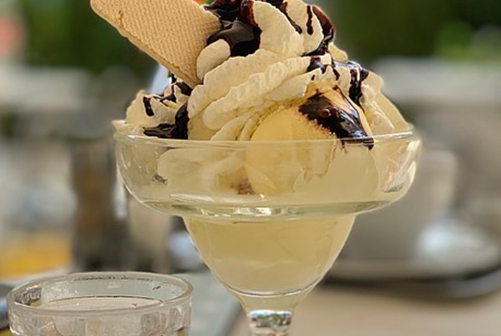 File: Ice cream with whipped cream, chocolate syrup, and a wafer (cropped).jpg Description English: A cocktail glass of ice cream with whipped cream, chocolate syrup, and a wafer Author Nicolas Ettlin This file is licensed under the Creative Commons Attribution-Share Alike 4.0 International license. https://creativecommons.org/licenses/by-sa/4.0/deed.en https://commons.wikimedia.org/wiki/File:Ice_cream_with_whipped_cream,_chocolate_syrup,_and_a_wafer_(cropped).jpg