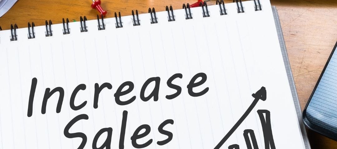 notebook on a desk with “increase sales” and an upward trending sales report written on it