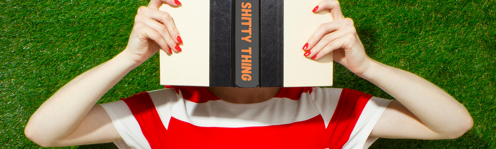 Woman holding an open book in front of her face, hiding behind it. The spine of the book reads Every Shitty Thing. She wears a stark red and white horizontal striped t-shirt and a green grass wall is the backdrop.