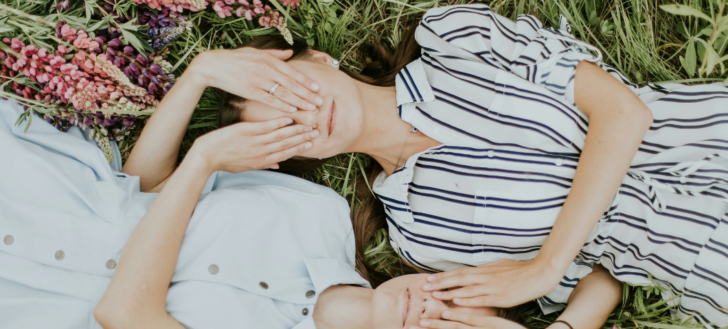 two girls lying down with their hands over each other’s eyes