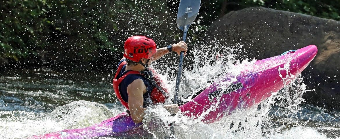 Fergus launching his whitewater kayak over a rock in a rapid