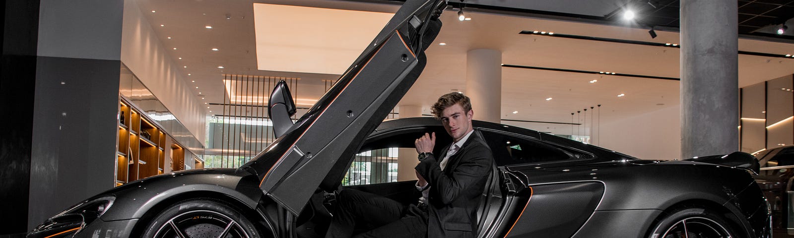 Handsome young man with a black and orange supercar