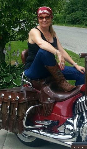 Photo of author, wearing cowboy boots, jeans and a red bandana on a red Indian motorcycle.