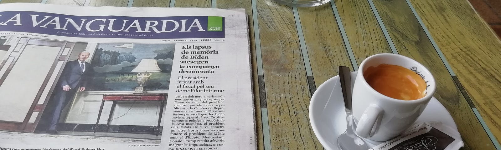 A newspaper sits on a cafe table, next to a cup of coffee