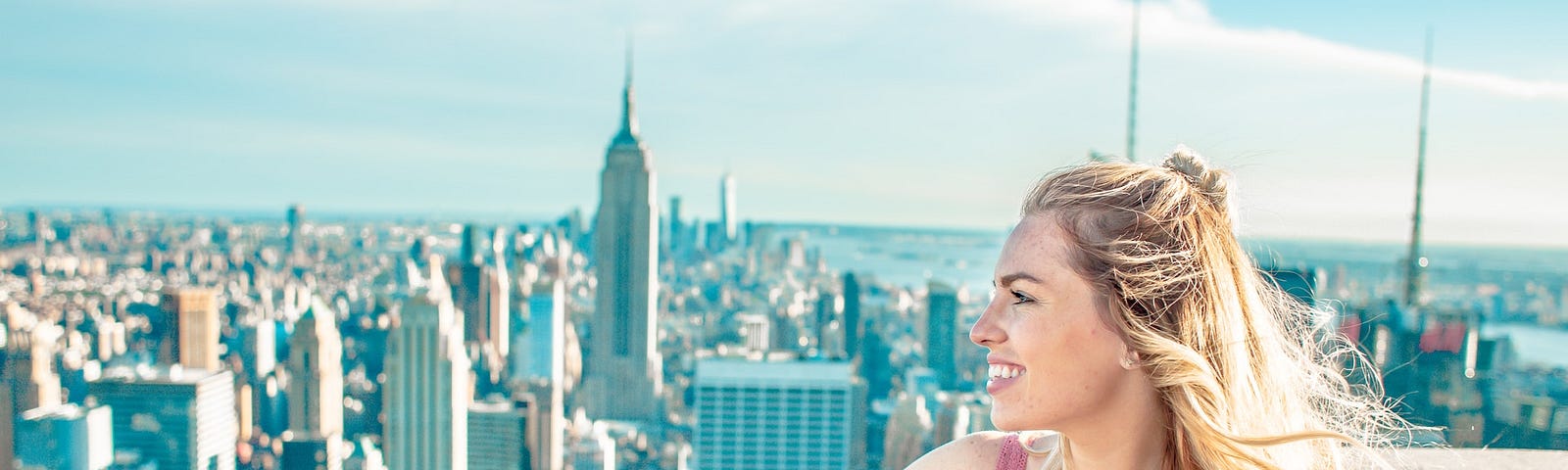 A woman at the top of a building overlooking the New York Skyline