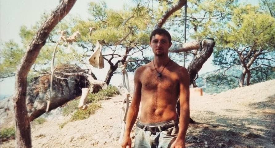 22-year-old Gentry Bronson standing shirtless in boots and shorts on the Aegean coastline of Turkey near Fethiye