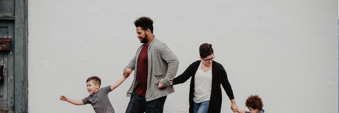 Family Of Four Walking At The Street