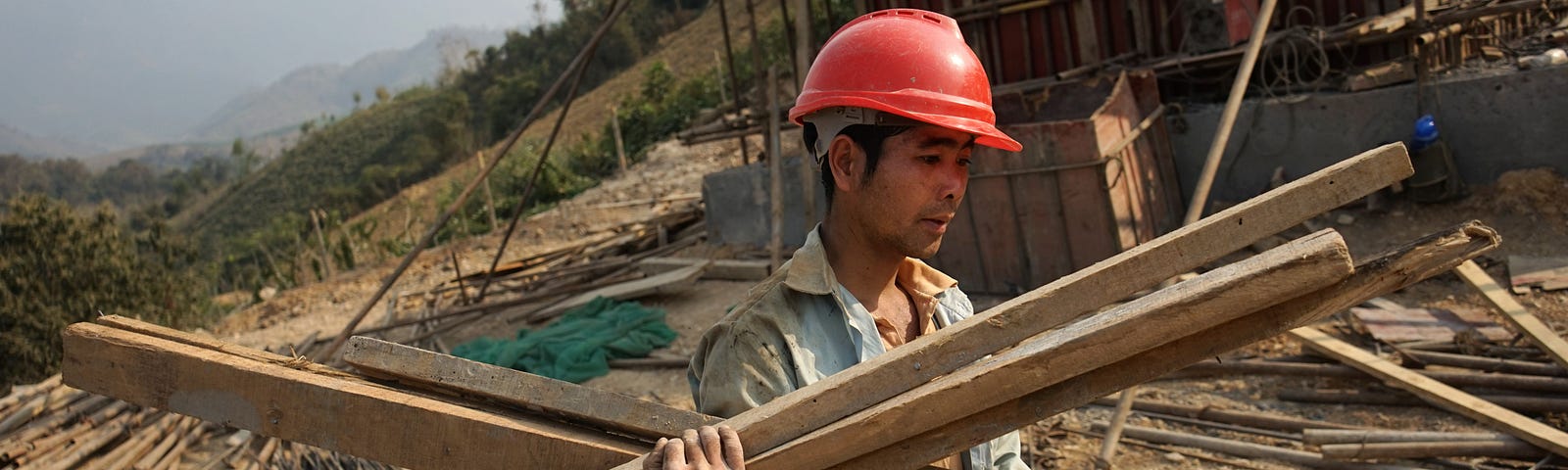 A Chinese worker carrying materials for the first rail line linking China to Laos.