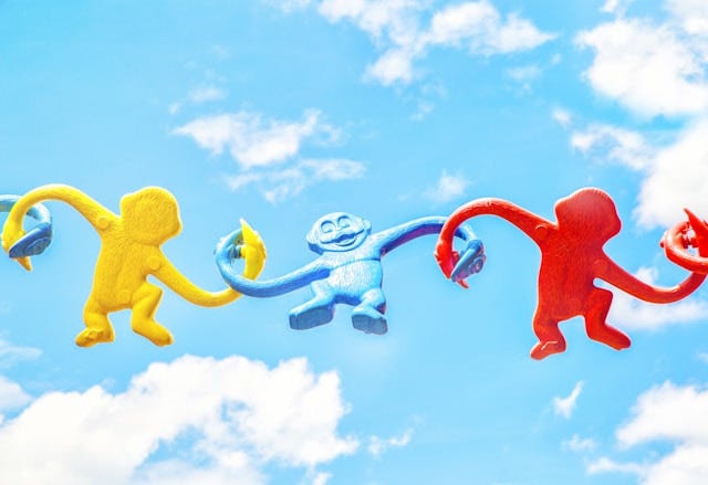 3 plastic monkeys holding hands in the air