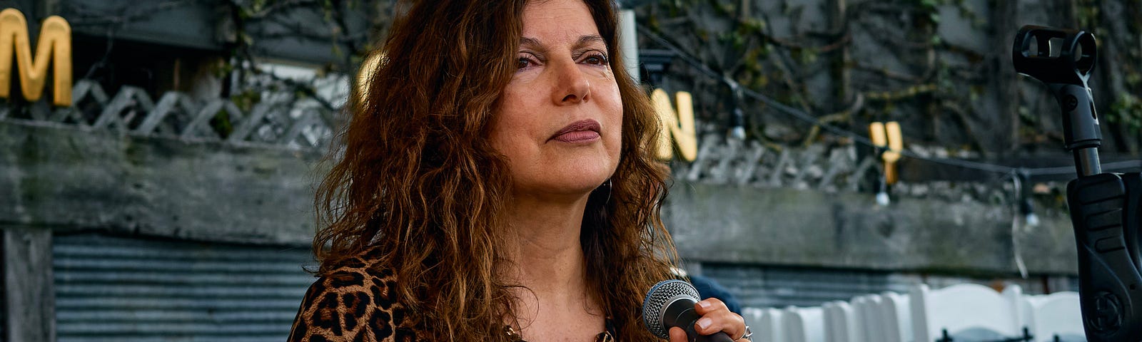 Woman on an outdoor stage holding a microphone.