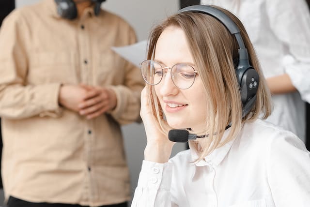 A woman wearing glasses and a headset taking calls.
