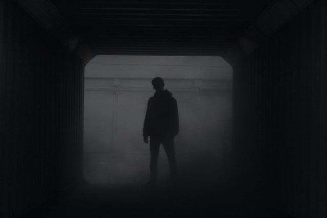 A shadow figure standing in a hallway in the mist.