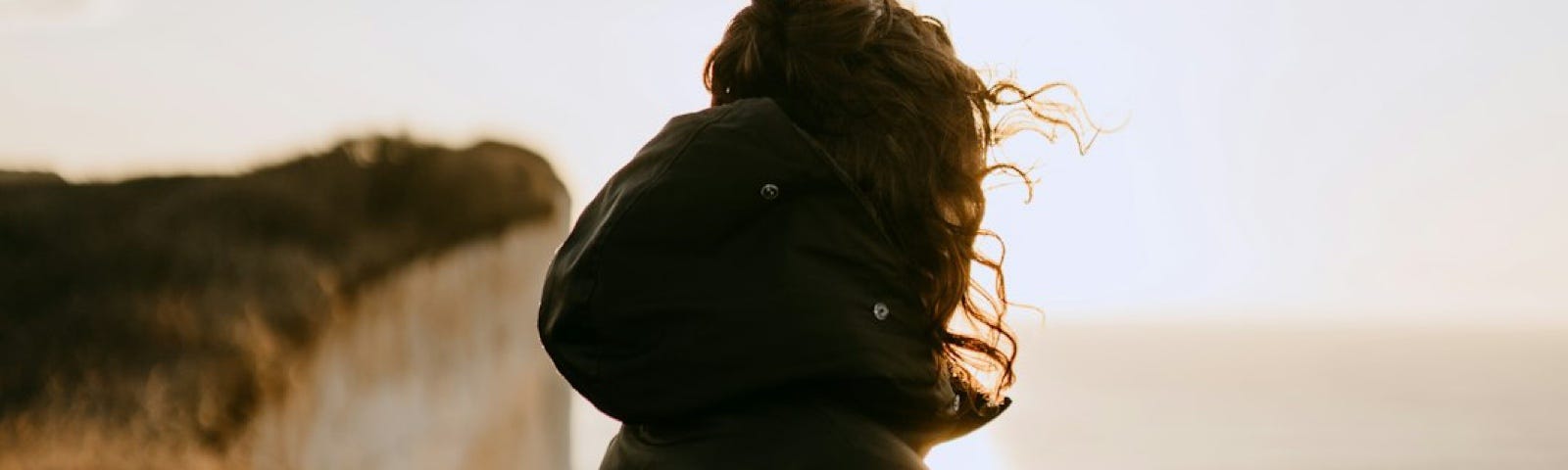 Image of a person starring into the ocean at sunrise, symbolizing dream, hope and solitude.