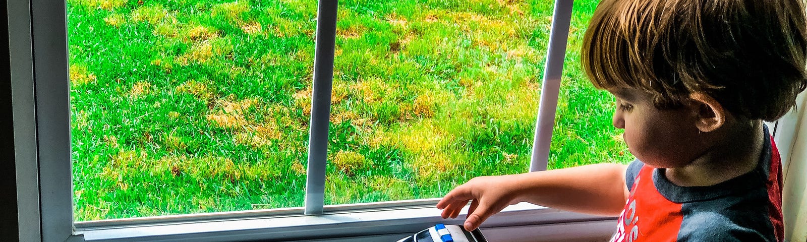 Image of child playing with a car by a window. Photo Credit — Brooke Moore