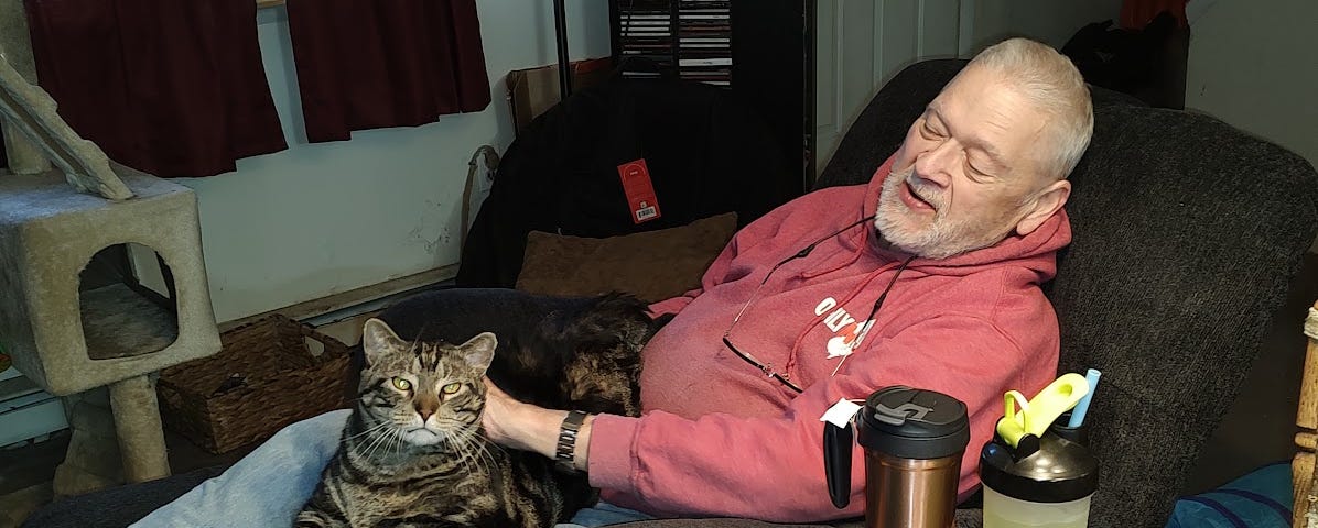 A picture of hubby Ted in his new recliner. Gus, our grey tabby, is sitting on his lap