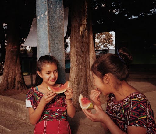 Two young girls eating watermelon.
