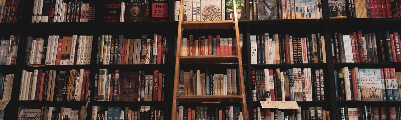 brown wooden ladder leaning on bookcase filled with books