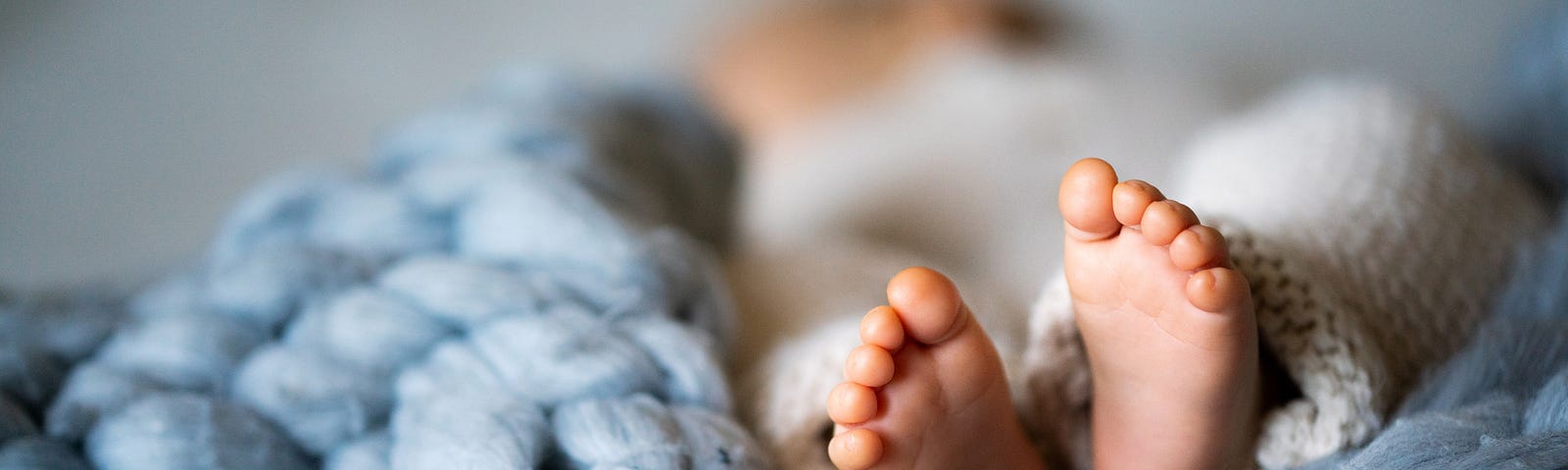 Feet of a newborn baby lying on a warm blanket.