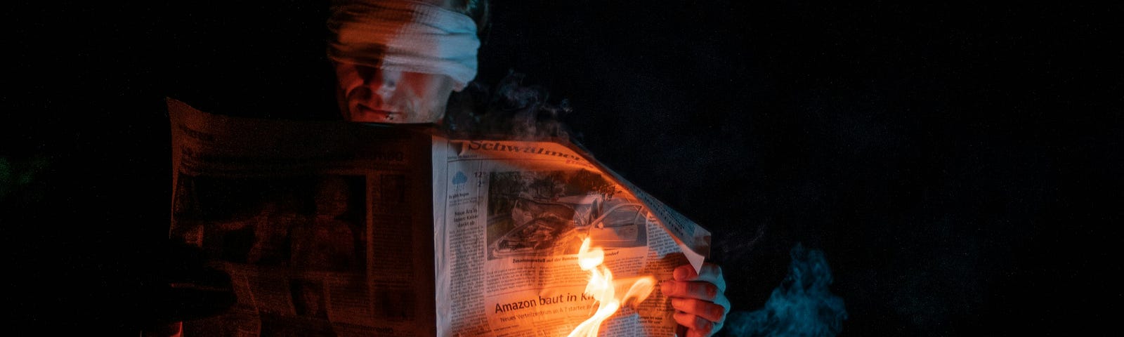 Person holds a newspaper that is on fire.