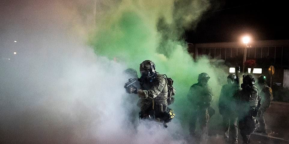 Federal agents with launching weapons amid a cloud of green fog