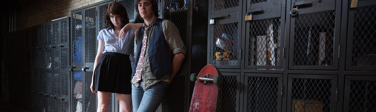 An urban youth couple standing in front of school lockers.