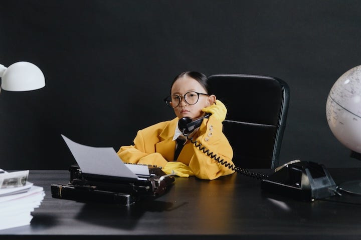 Little Asian girl dressed as business executive on the phone