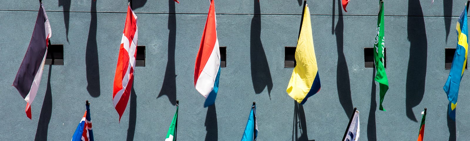 Image of assorted colored flags on a wall during day time