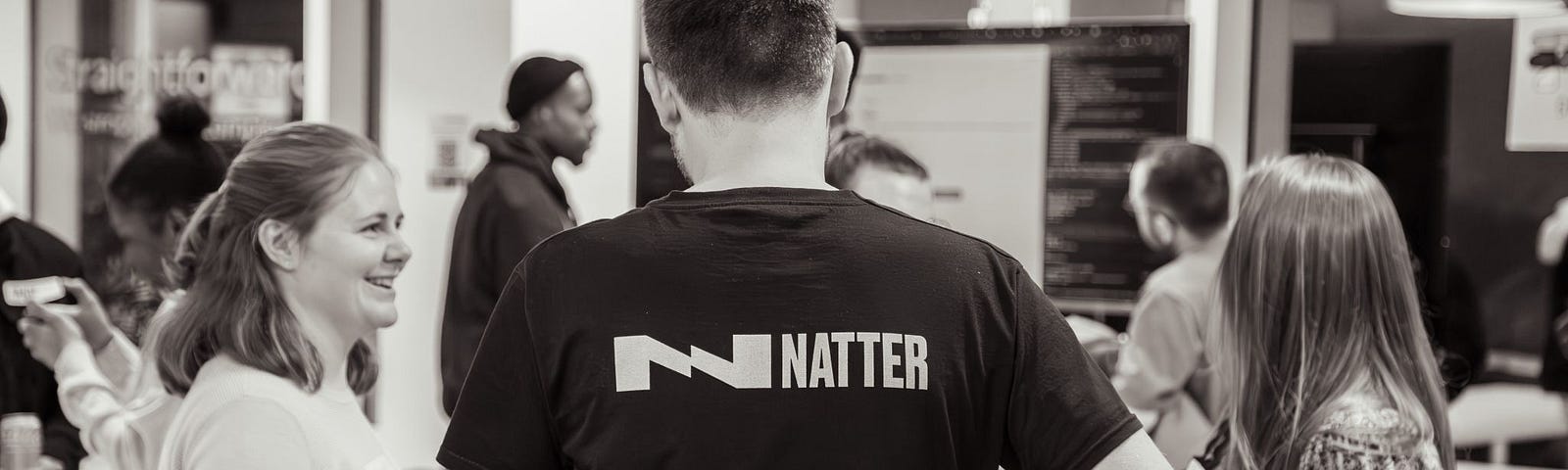 Natter community volunteer showing the branding on the back of their shirt chatting with 2 girls who attended the event