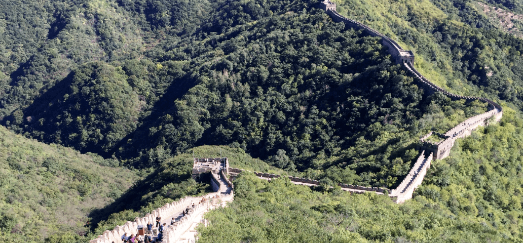 Great Wall of China receding to horizon with green forests on both sides