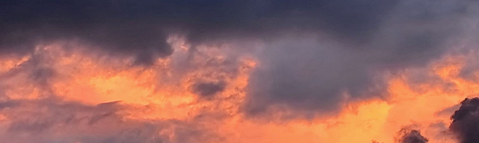 photo of night sky with orange clouds through dark purple clouds