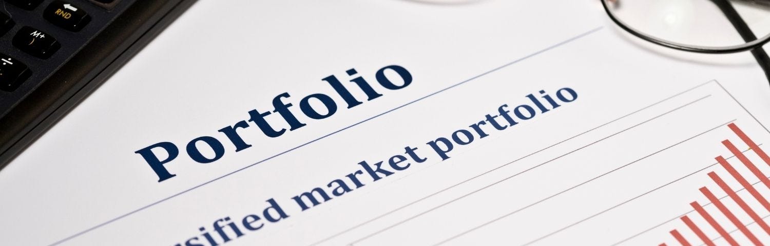 Image of a portfolio with eye glasses and a writing pen on a desk.