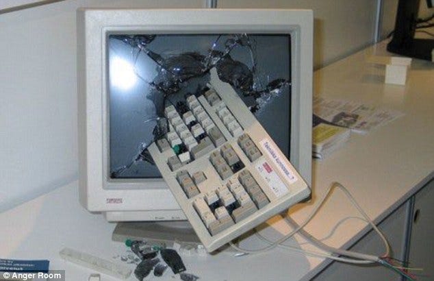 An old computer monitor with a keyboard smashed through the screen