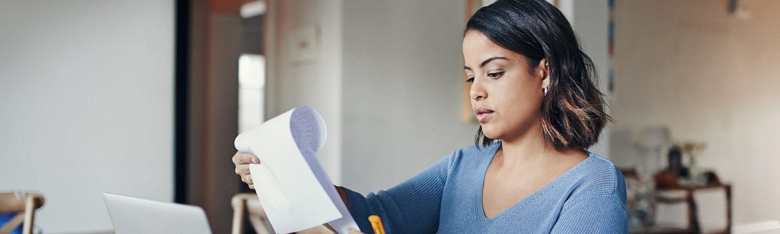 An individual on their laptop sifting through papers.