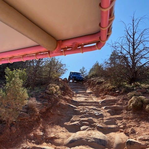 A Jeep is on the top of a steep, rocky hill about to come down showing how powerful momentum can be.