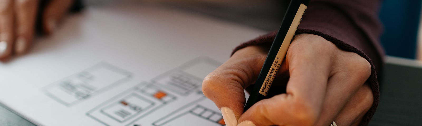 a close-up of a person drawing screens on a piece of paper with a drawing pen.