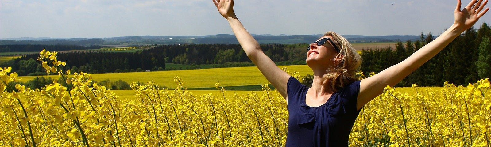 Woman with raised hands in a field of yellow flowers