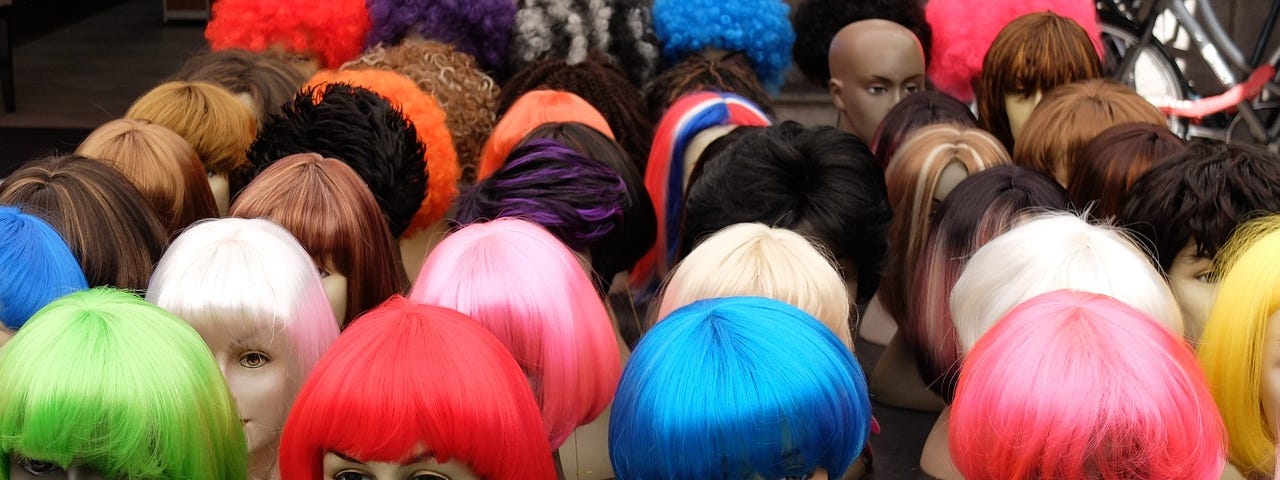 Rows of colorful wigs in various styles on female mannequin heads.