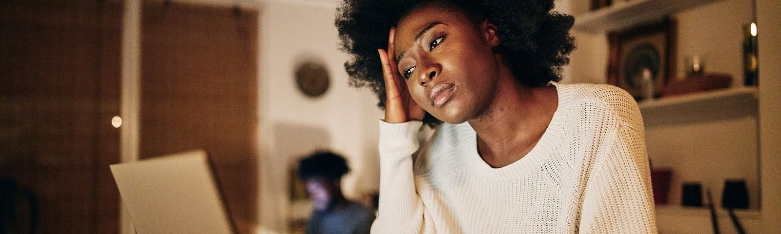 An African American woman freelancer working on a laptop, looking stressed