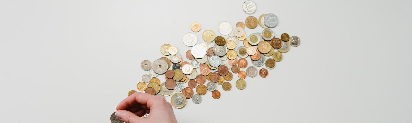 A black piggy bank with some coins. A hand is putting coins in it.