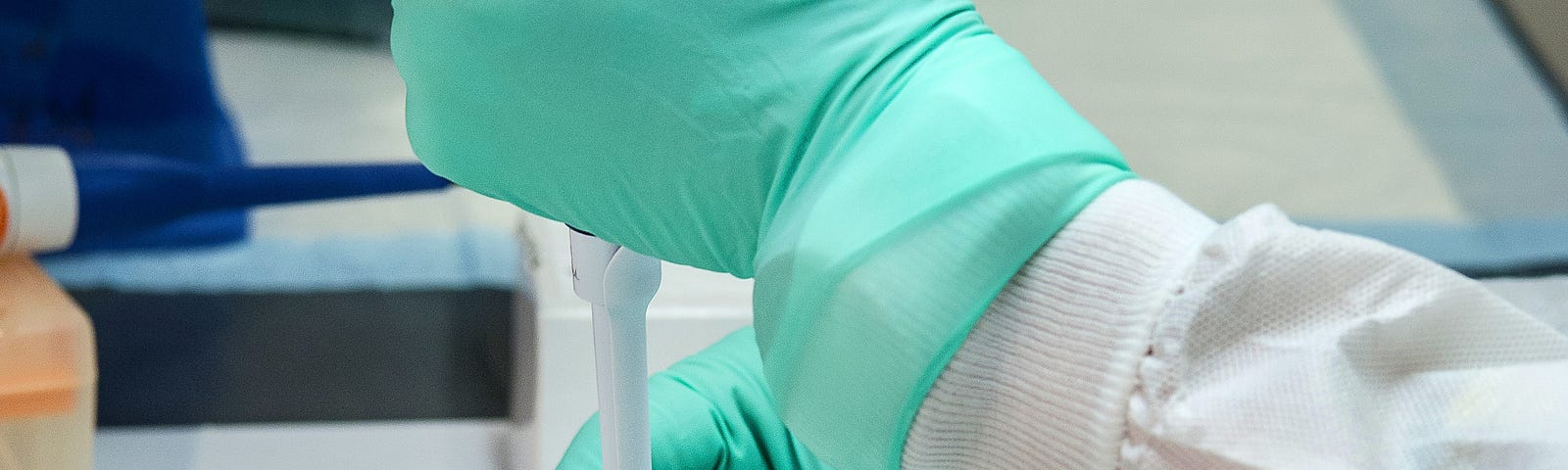 Person pipetting with gloved hands