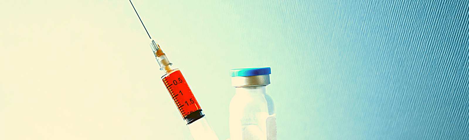 Hand holding syringe and vial on blue background