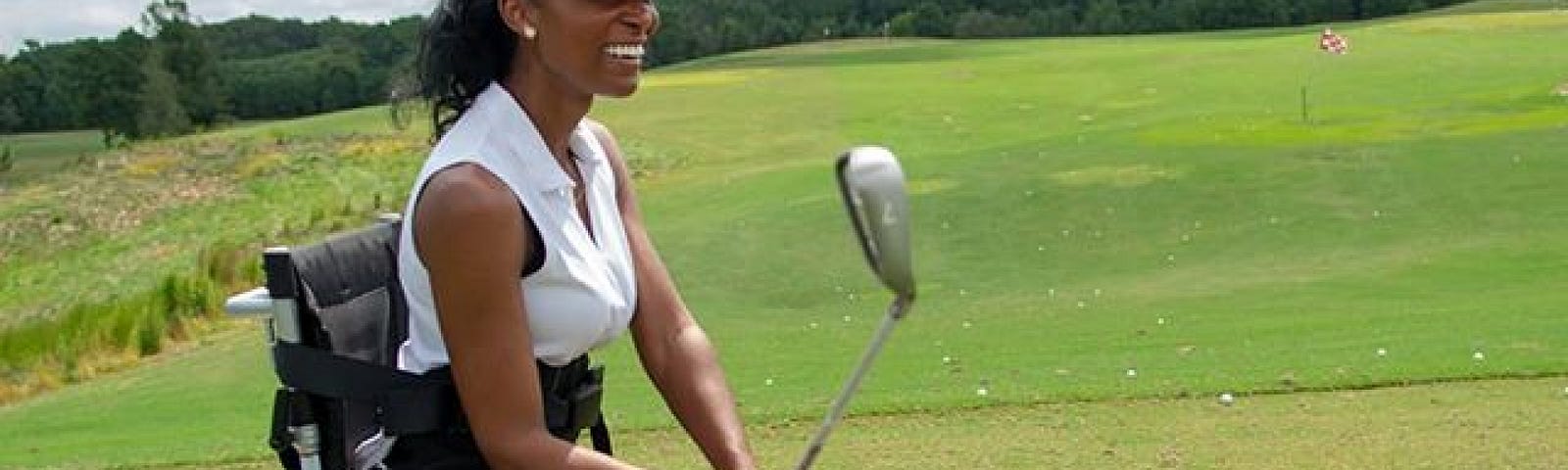 Tae McKenzie on golf course with assistive equipment on wheels holding golf club.