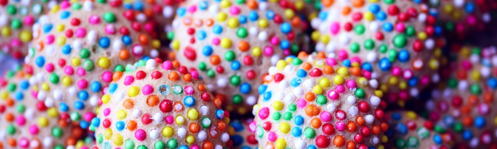 Pink balls of confectionery covered in multi-coloured hundreds and thousands.