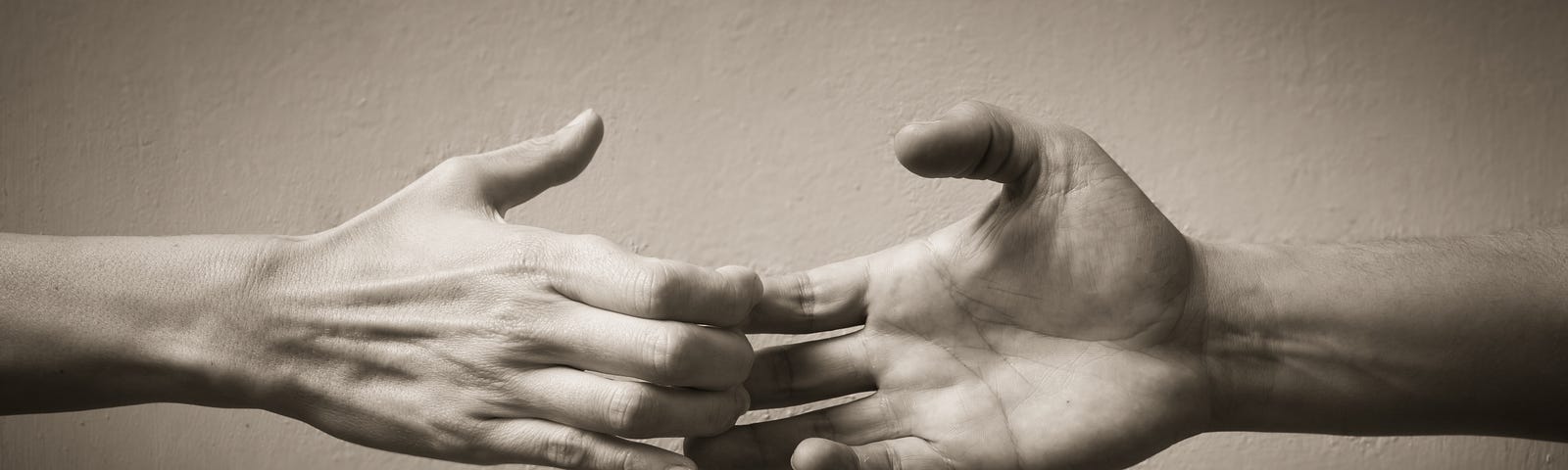 A black and white image of two hands pulling apart, as if there were until just now holding each other but now drift apart.