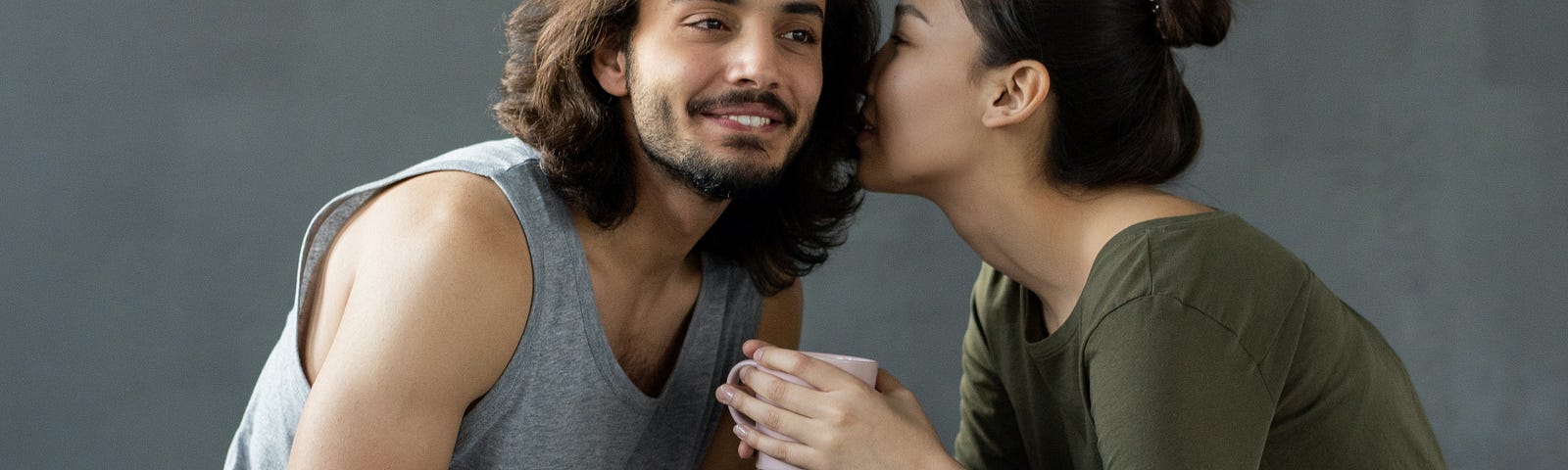 Man with beard, smile, holding mug listening to woman whispering